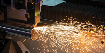 Industrial laser cutting machine cutting metal pipe with sparks flying